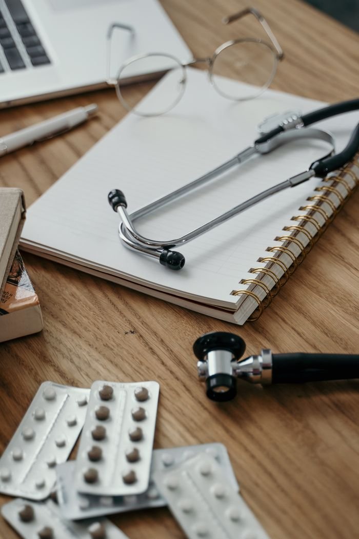 Stethoscope, pills, and notebook on a doctor's desk, showcasing a clinical setting.